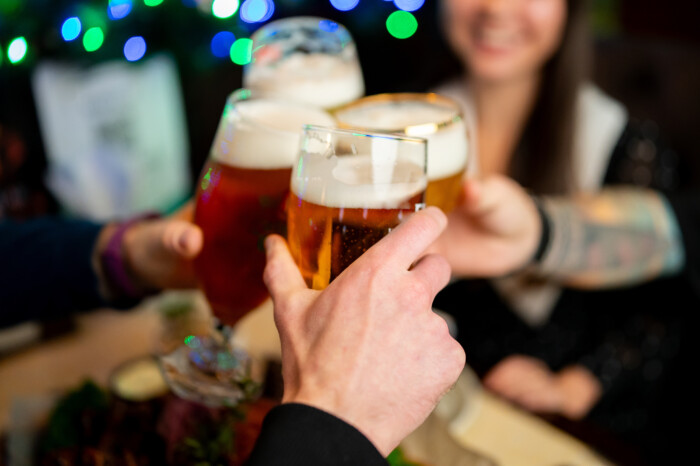 A Group Of Friends Making A Celebratory Beer Toast In A Lively B